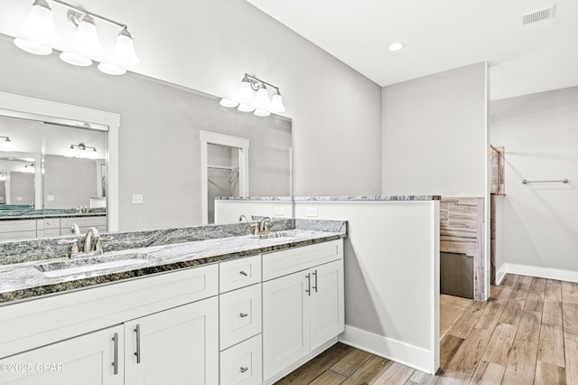 bathroom with double vanity, visible vents, wood finished floors, and a sink