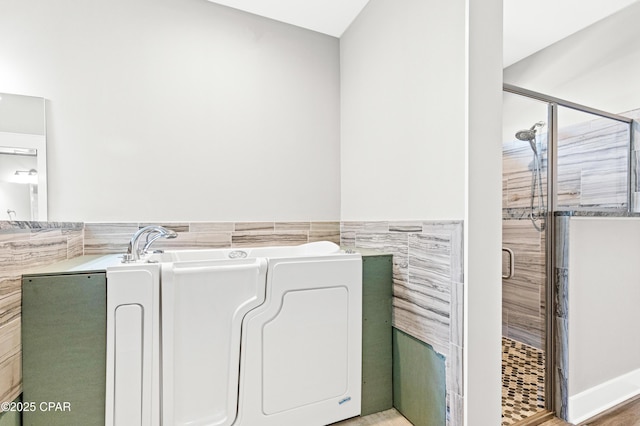 bathroom featuring tile walls, a wainscoted wall, a bathtub, and a shower stall