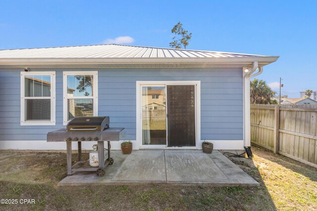 view of exterior entry featuring a patio area, metal roof, and fence