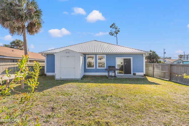 rear view of house with a shed, an outbuilding, a fenced backyard, metal roof, and a lawn