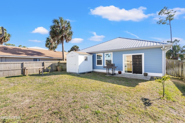 back of house featuring metal roof, a fenced backyard, a lawn, an outbuilding, and a shed