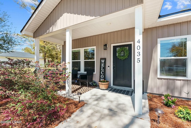 view of exterior entry featuring covered porch and board and batten siding