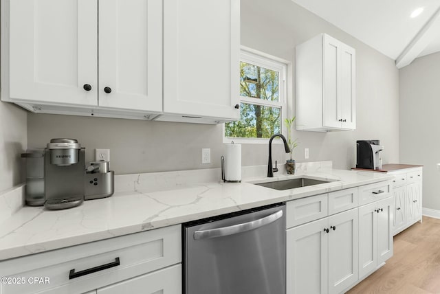 kitchen featuring white cabinetry, a sink, dishwasher, light wood-style flooring, and light stone countertops