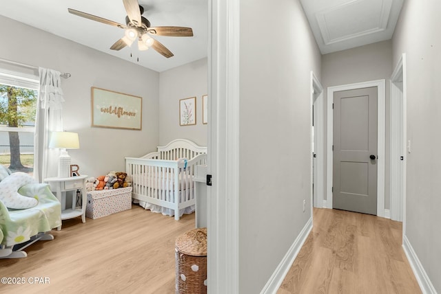 bedroom featuring baseboards, a ceiling fan, light wood-style flooring, and attic access