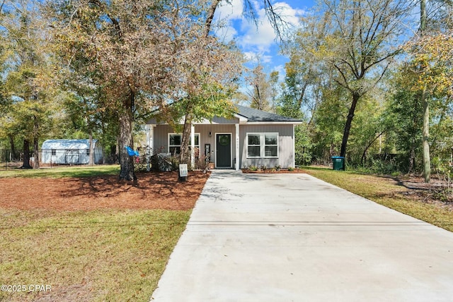 view of front facade with driveway, fence, and a front yard