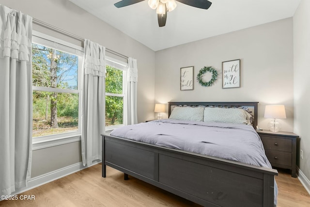 bedroom with multiple windows, wood finished floors, ceiling fan, and baseboards