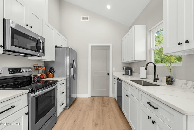 kitchen featuring vaulted ceiling, stainless steel appliances, a sink, visible vents, and white cabinets