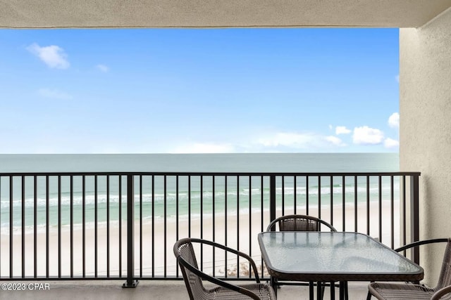 balcony with a water view and a view of the beach