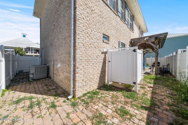 14205 Millcole Ave, Panama City Beach, FL 32413 - view of home's exterior with a fenced backyard, central AC unit, brick siding, and a patio area