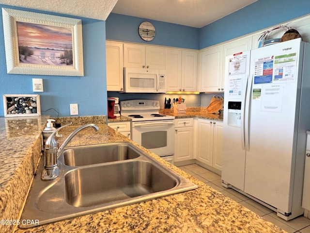 kitchen featuring white appliances, light tile patterned floors, white cabinetry, and a sink