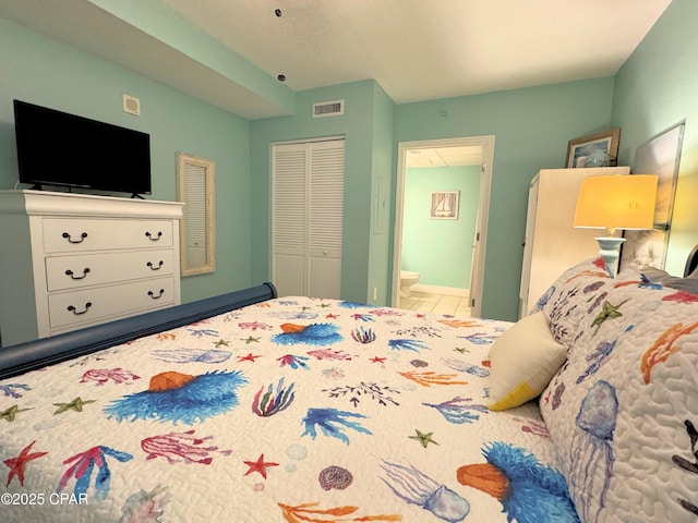 tiled bedroom featuring visible vents, ensuite bathroom, and a closet