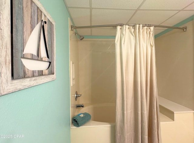 full bath with a drop ceiling and shower / tub combo