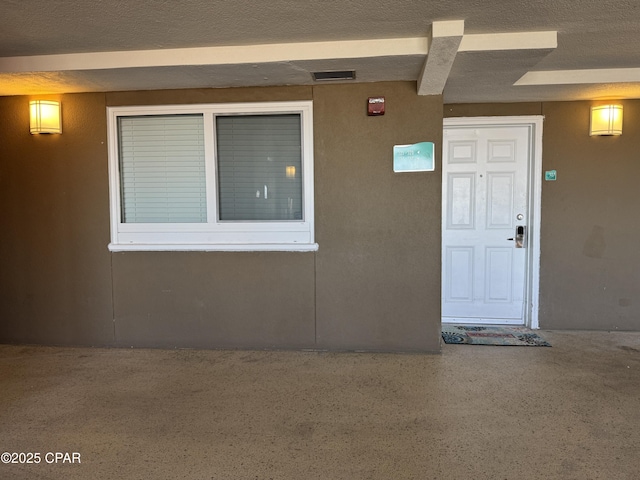 entrance to property featuring visible vents and stucco siding