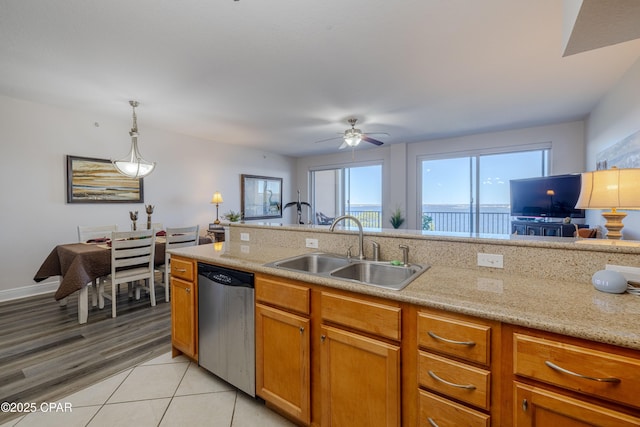 kitchen featuring open floor plan, stainless steel dishwasher, hanging light fixtures, a sink, and ceiling fan