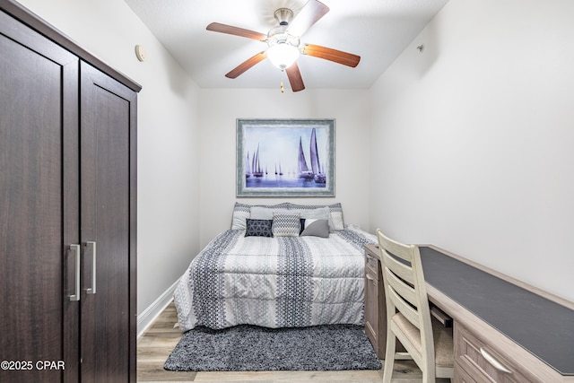 bedroom with baseboards, light wood-type flooring, and ceiling fan