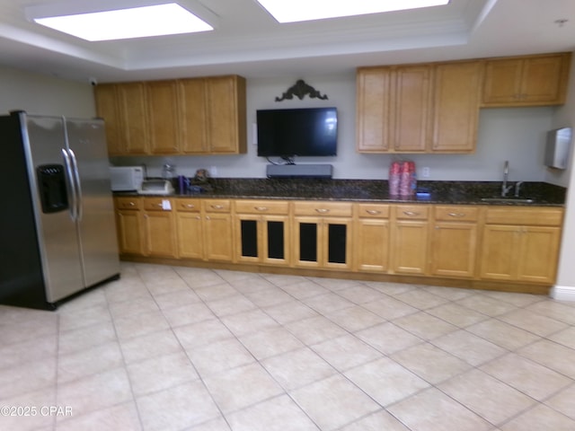 kitchen with dark stone counters, a raised ceiling, a sink, stainless steel refrigerator with ice dispenser, and white microwave
