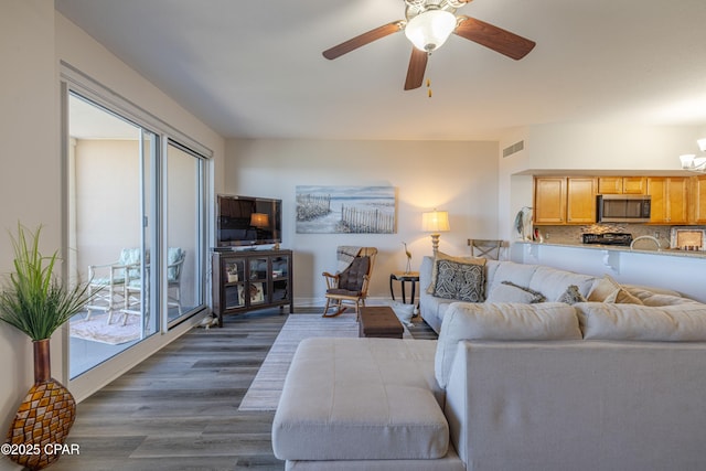 living area featuring dark wood finished floors, visible vents, and a ceiling fan