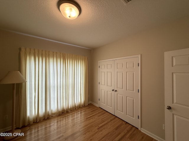 2557 Woods View Dr, Marianna, FL 32446 - unfurnished bedroom with baseboards, a textured ceiling, a closet, and wood finished floors
