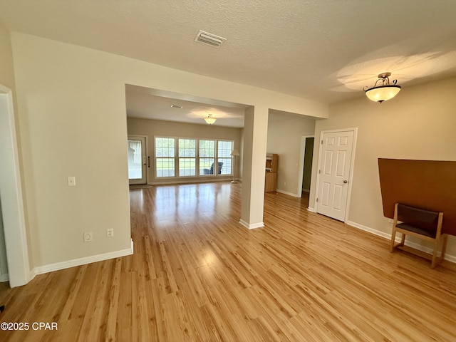 2557 Woods View Dr, Marianna, FL 32446 - empty room featuring a textured ceiling, baseboards, light wood finished floors, and visible vents