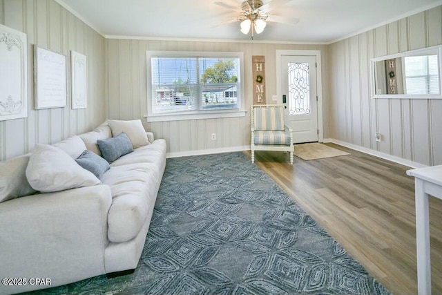 living area featuring ornamental molding, ceiling fan, wood finished floors, and baseboards