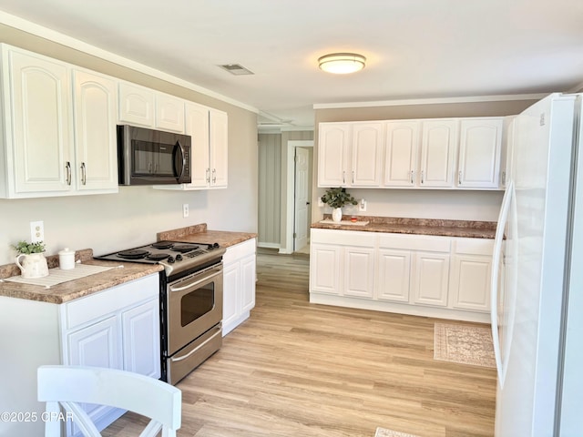 kitchen featuring stainless steel electric range oven, light wood-style floors, freestanding refrigerator, and white cabinetry