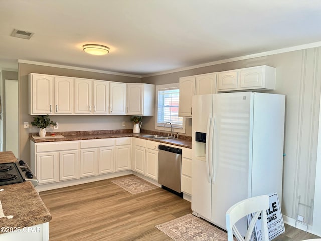 kitchen featuring crown molding, white refrigerator with ice dispenser, visible vents, dishwasher, and a sink