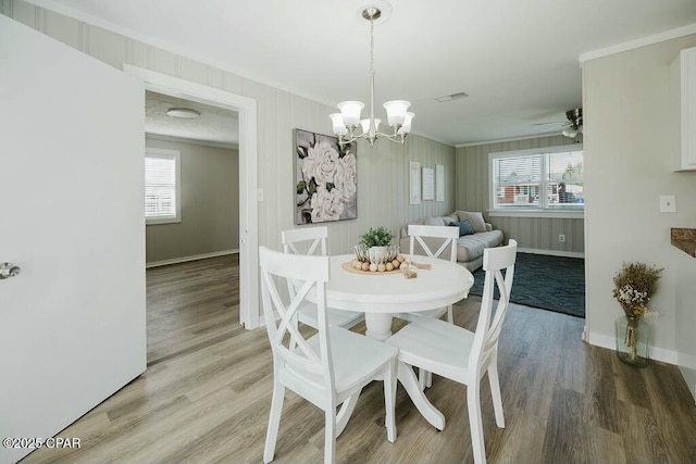 dining space with baseboards, plenty of natural light, crown molding, light wood-style floors, and visible vents
