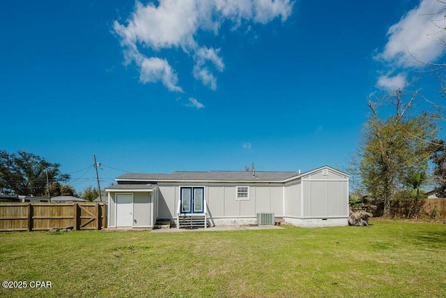 back of property featuring entry steps, central AC, fence private yard, and a lawn