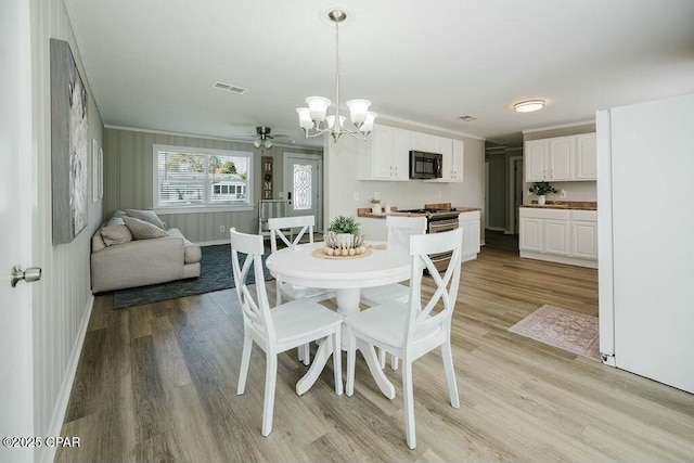 dining room featuring light wood-style flooring, crown molding, baseboards, and visible vents