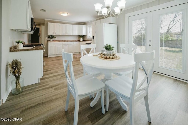 dining room with light wood-style floors, an inviting chandelier, and visible vents