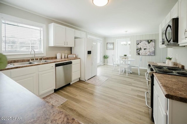 kitchen with white cabinets, a notable chandelier, a sink, light wood-type flooring, and stainless steel appliances