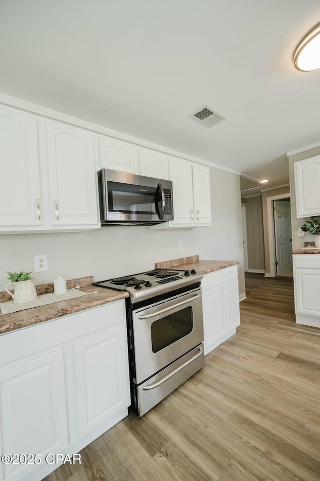 kitchen with light wood-style floors, visible vents, white cabinets, and appliances with stainless steel finishes