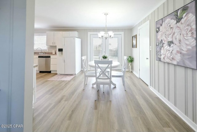 dining space featuring light wood-style flooring, a notable chandelier, and ornamental molding