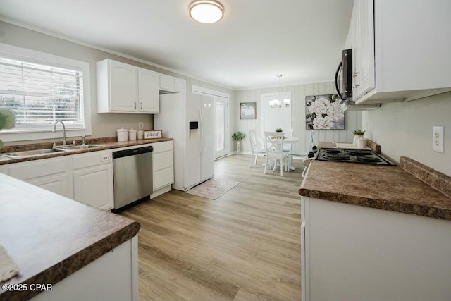 kitchen featuring an inviting chandelier, white refrigerator with ice dispenser, white cabinetry, dishwasher, and a sink