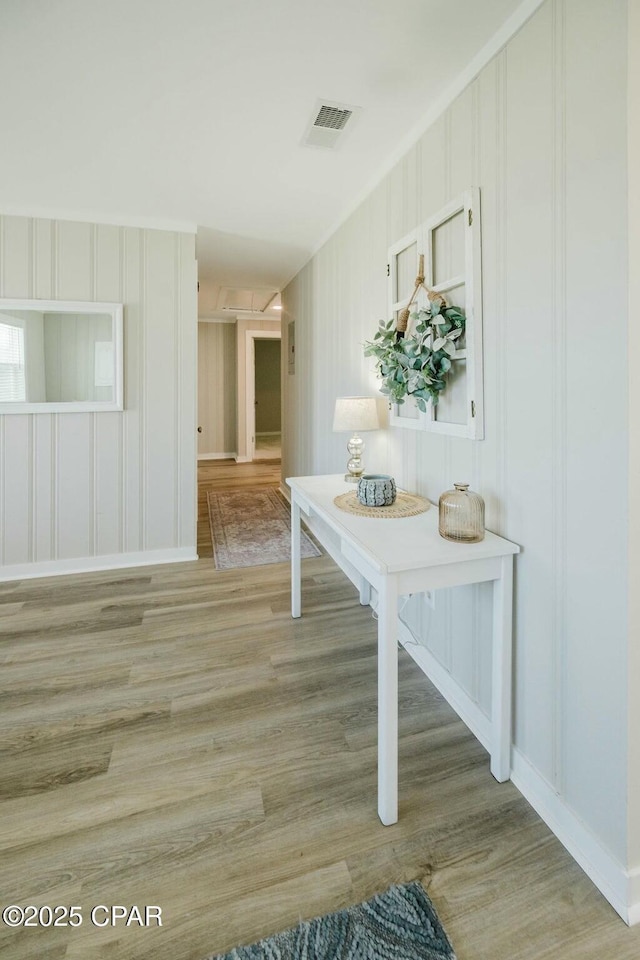 corridor featuring light wood-type flooring, attic access, baseboards, and visible vents
