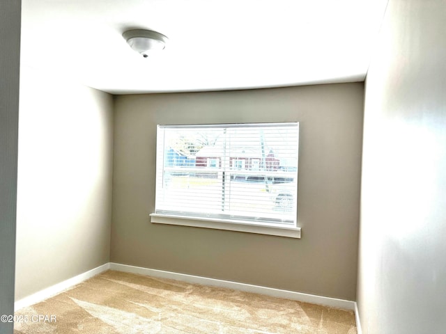 spare room with light colored carpet and baseboards