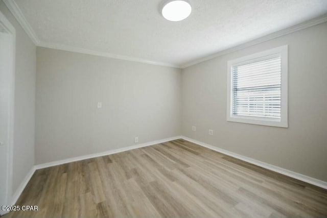 empty room featuring crown molding, wood finished floors, and baseboards