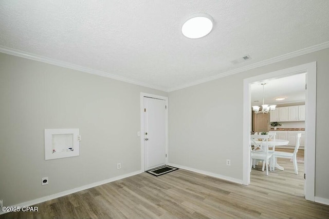 empty room with a textured ceiling, light wood-type flooring, visible vents, a chandelier, and baseboards