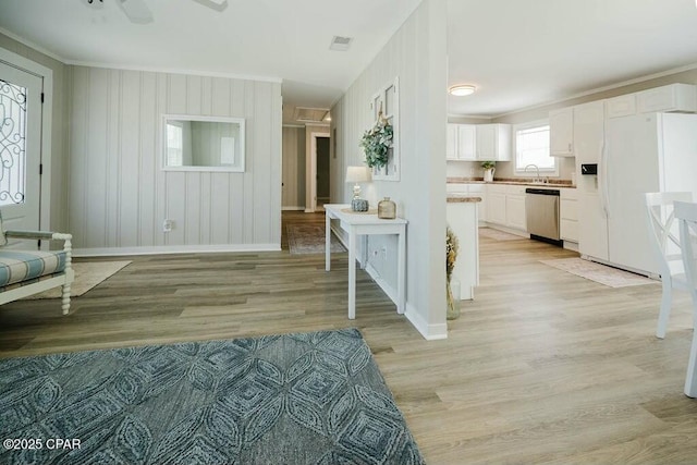 interior space featuring visible vents, baseboards, crown molding, and light wood-style flooring