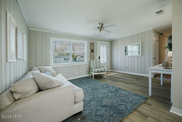 living area with visible vents, baseboards, and crown molding