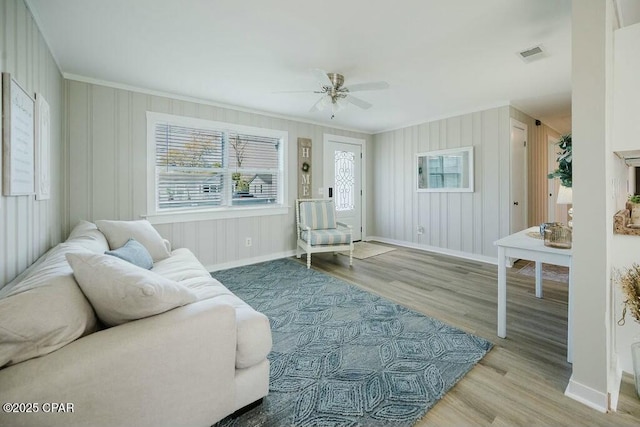living room featuring crown molding, visible vents, baseboards, and plenty of natural light
