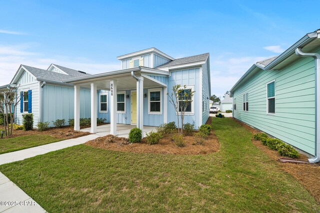 view of front of property featuring board and batten siding, an attached carport, a shingled roof, and a front lawn