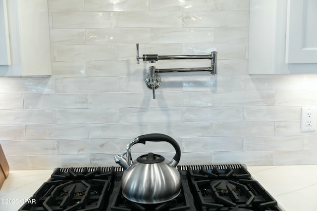 interior details featuring white cabinets, backsplash, and light stone countertops