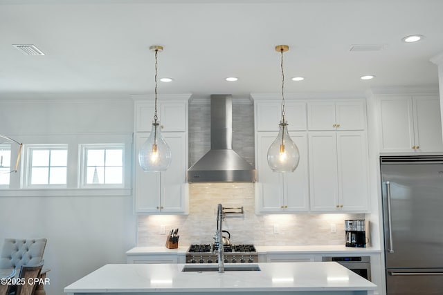 kitchen featuring a sink, visible vents, backsplash, wall chimney range hood, and appliances with stainless steel finishes