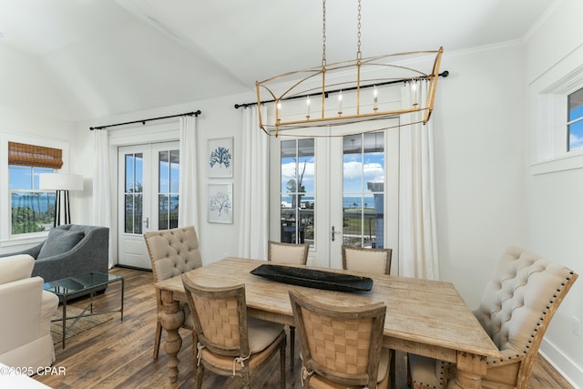 dining space with lofted ceiling, a notable chandelier, wood finished floors, and french doors