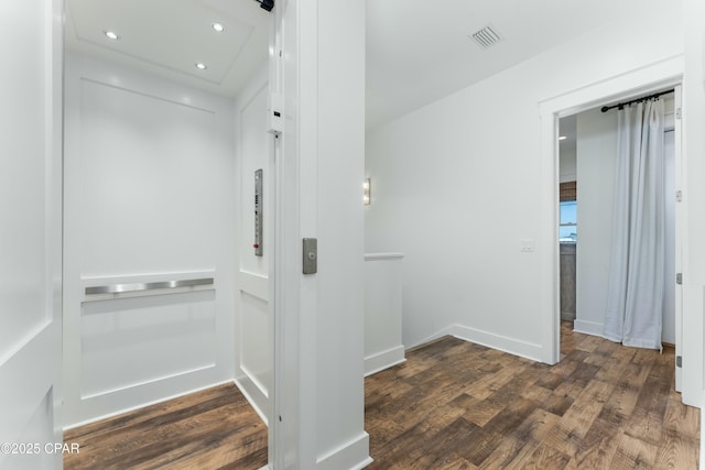 corridor featuring recessed lighting, visible vents, elevator, baseboards, and dark wood finished floors