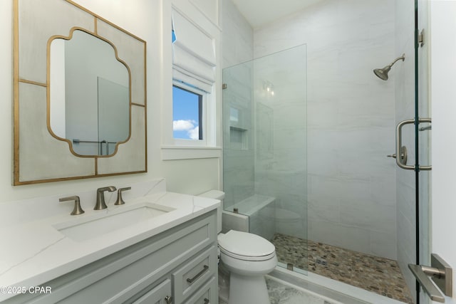 full bathroom featuring toilet, marble finish floor, tiled shower, and vanity