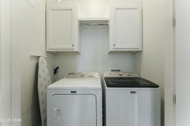 clothes washing area with washer and dryer and cabinet space