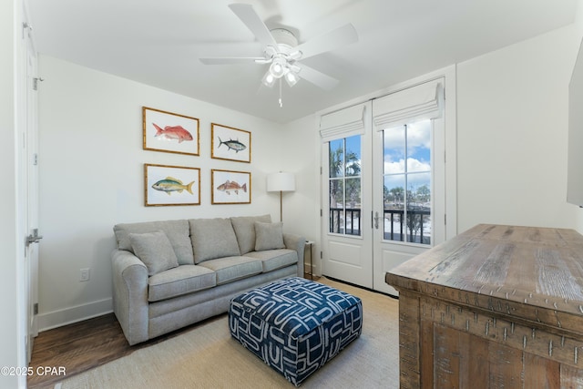 living room with wood finished floors, ceiling fan, a water view, and baseboards