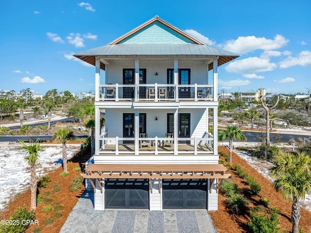 view of front of home with a balcony, a standing seam roof, metal roof, decorative driveway, and an attached garage